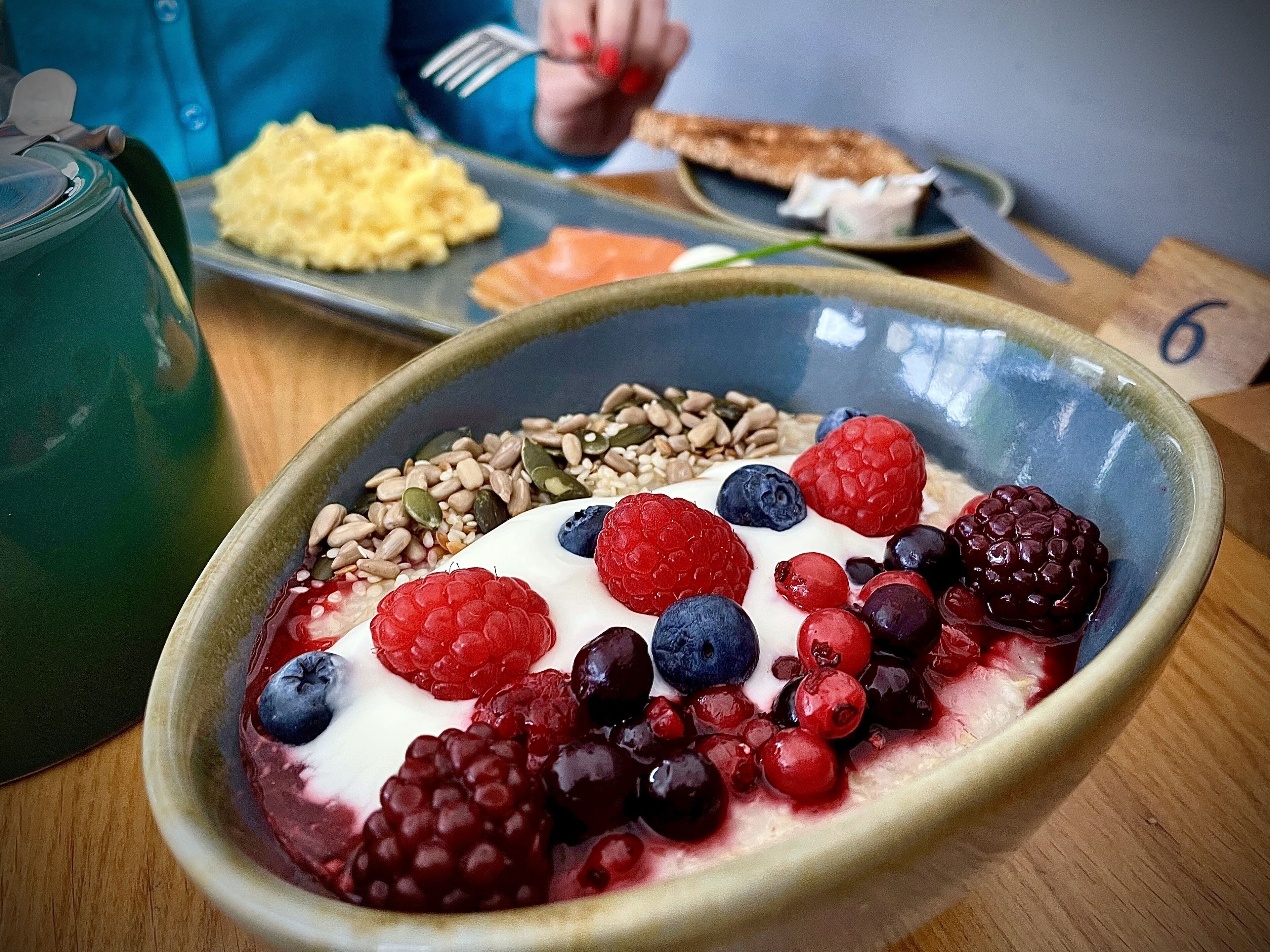 A bowl of yogurt topped with berries and seeds.