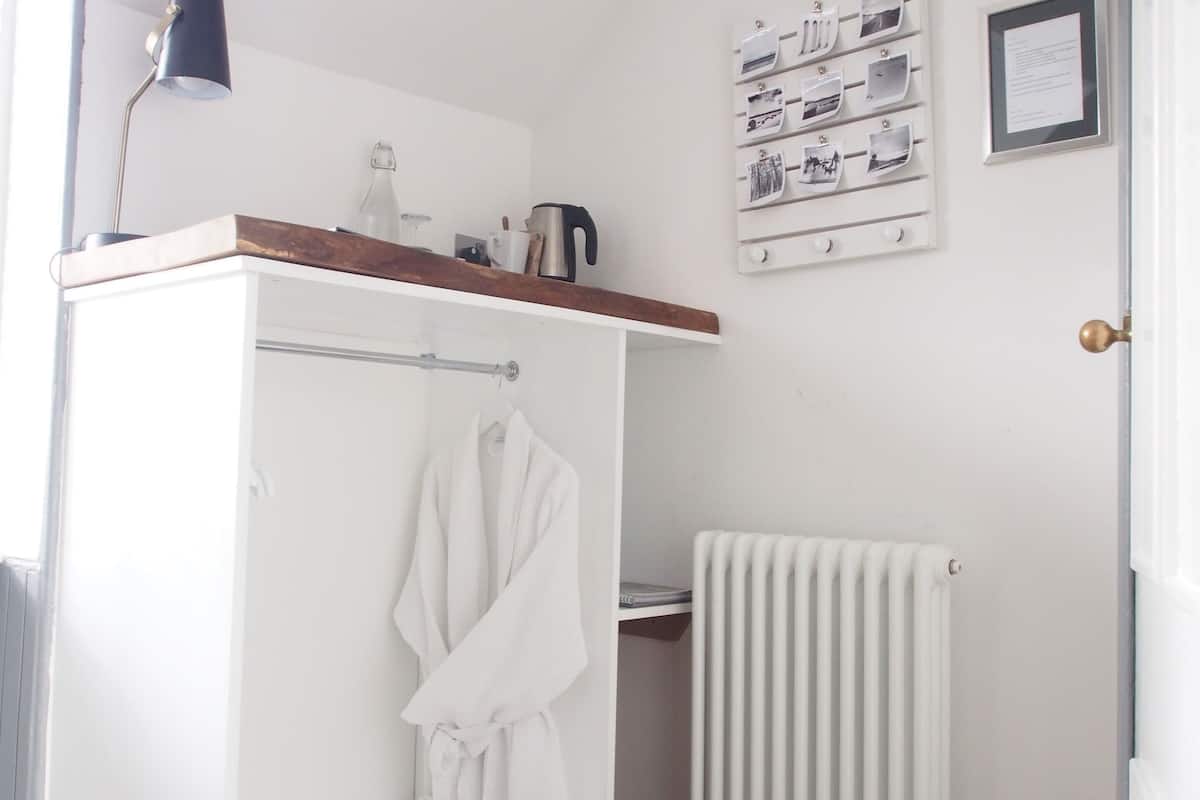 Un baño moderno con ducha, toallero, radiador y repisa con artículos de aseo.
