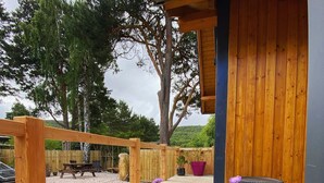 Una pérgola de madera con un sendero de grava, rodeada de flores moradas y una valla de madera.