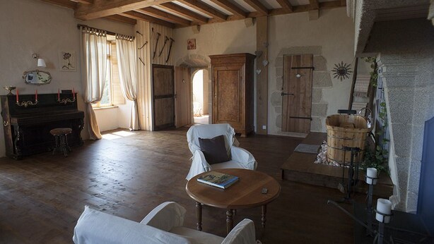 A rustic room with a wooden floor, a piano, a fireplace, and a stone wall. - Logis De Riparfonds (Bressuire)