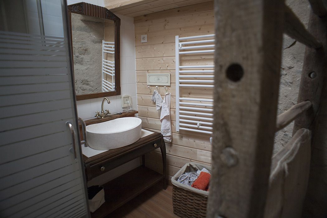 A compact bathroom with a wooden vanity, a round sink, a mirror, and a towel rack.