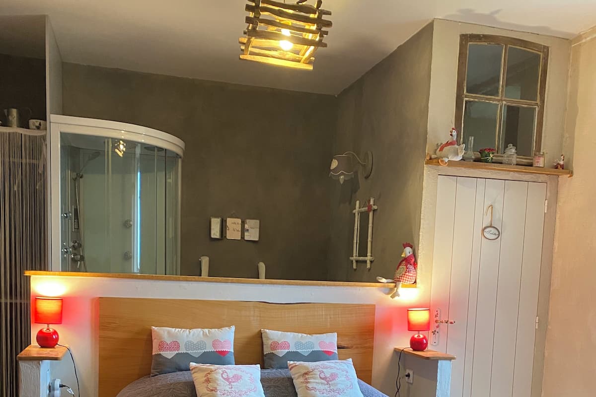 Un dormitorio con una cama grande, lámparas de noche, cabecera de madera, ventana y armario.