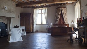 A room with a fireplace, a piano, and a large window with curtains. - Logis De Riparfonds (Bressuire)