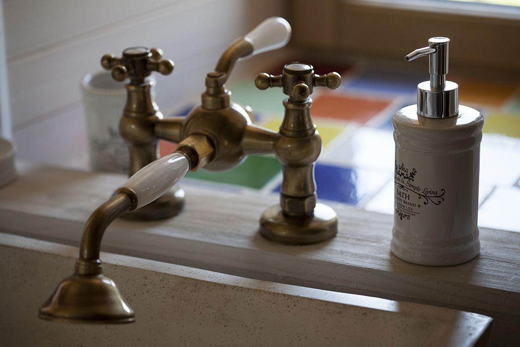 Une salle de bain avec des robinets en laiton d’époque et un distributeur de savon.