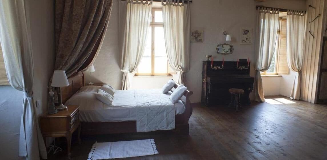 A bedroom with a bed, a piano, and curtains.