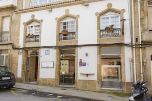 A hotel with a traditional facade, featuring multiple windows with flower boxes, a visible entrance, and a sign indicating a restaurant on the ground floor. - Hotel Restaurante Elisardo (Noia)