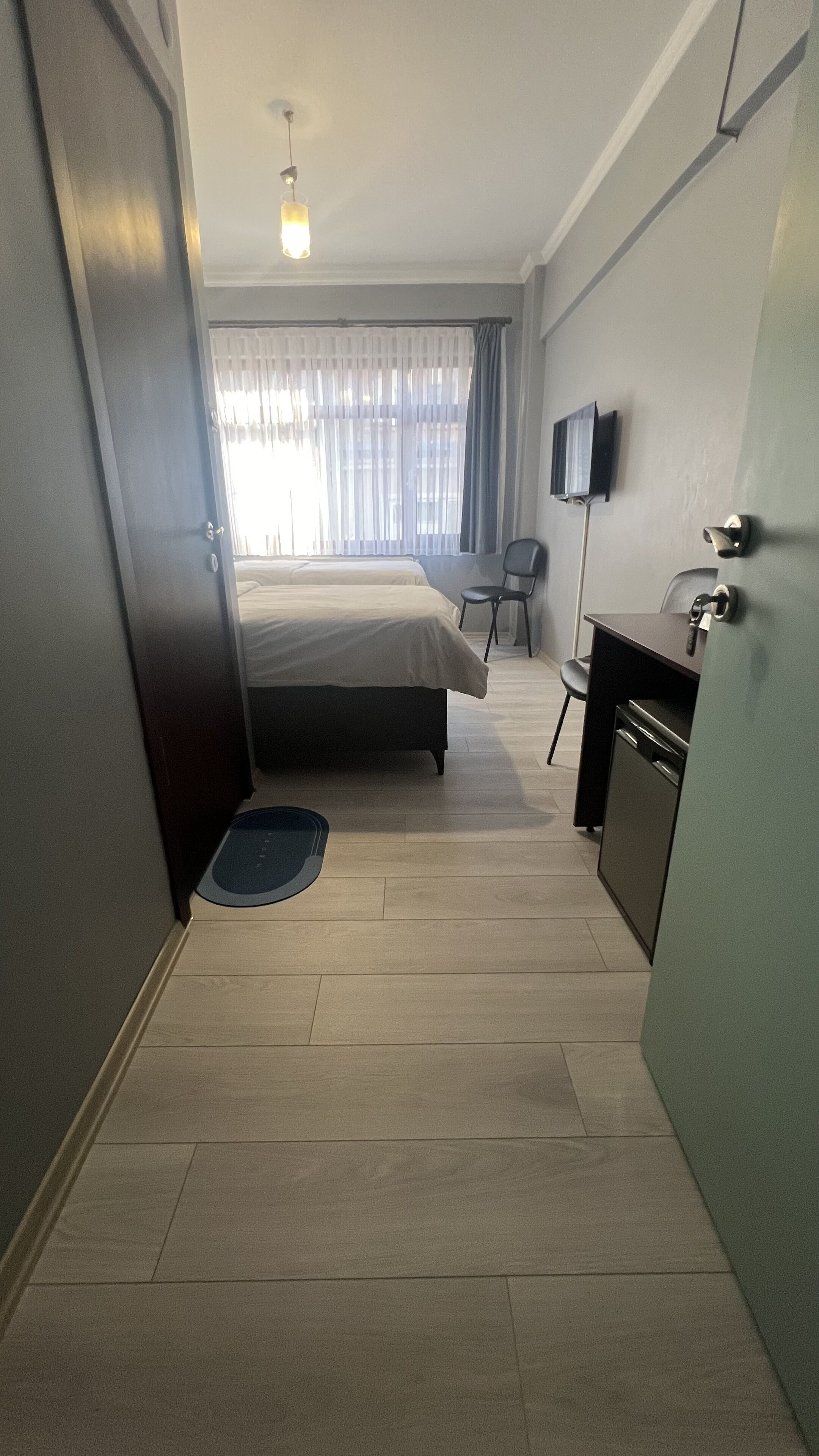 A hotel room with a bed, a desk, a chair, a television, and a door.