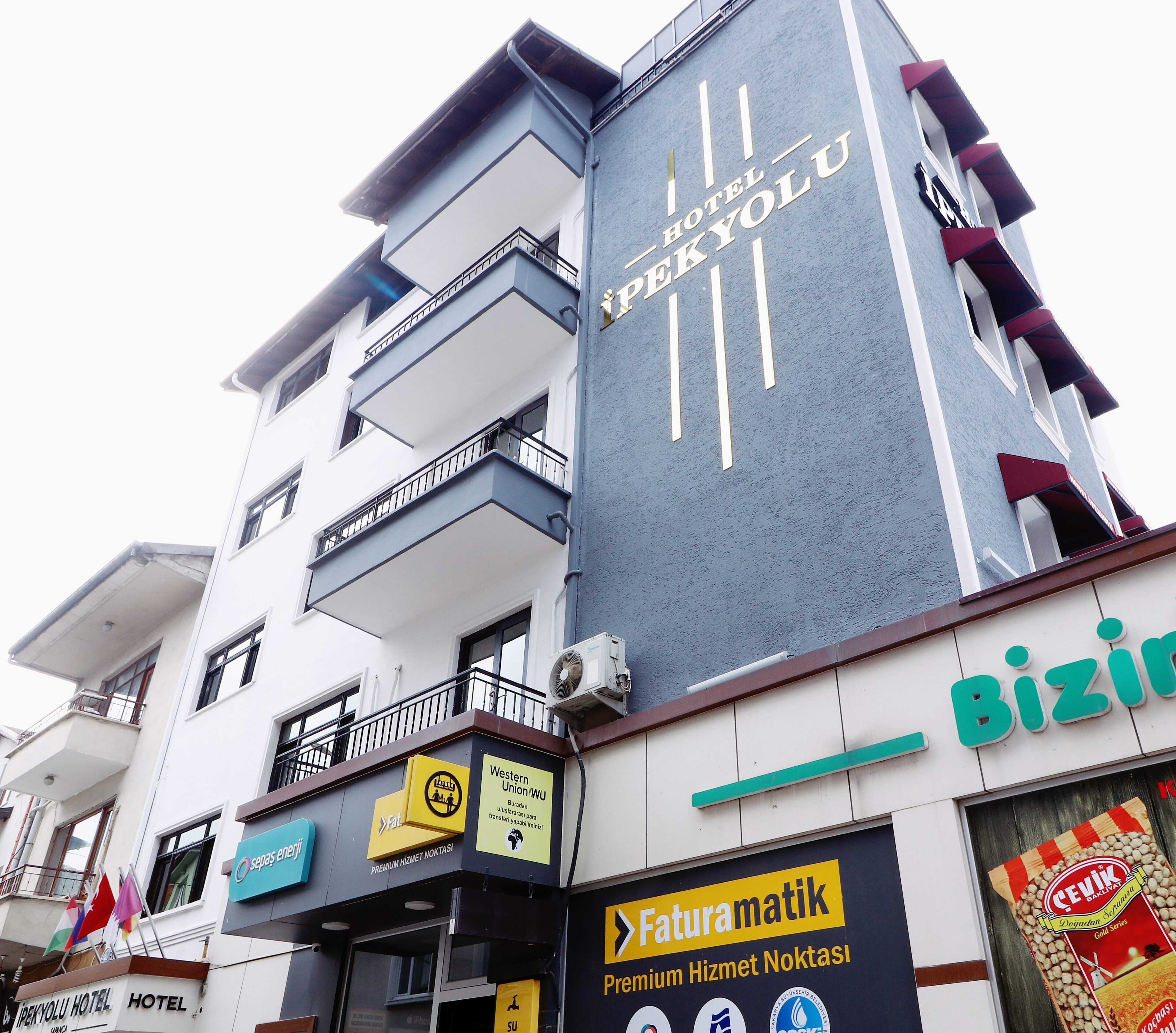 Ein mehrstöckiges Hotel mit Balkonen, einem sichtbaren Schild für 'Hotel SpreeYolu' sowie Geschäften, darunter 'Faturamatik' und 'Biz'.