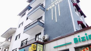 Ein mehrstöckiges Hotel mit Balkonen, einem sichtbaren Schild für 'Hotel SpreeYolu' sowie Geschäften, darunter 'Faturamatik' und 'Biz'.