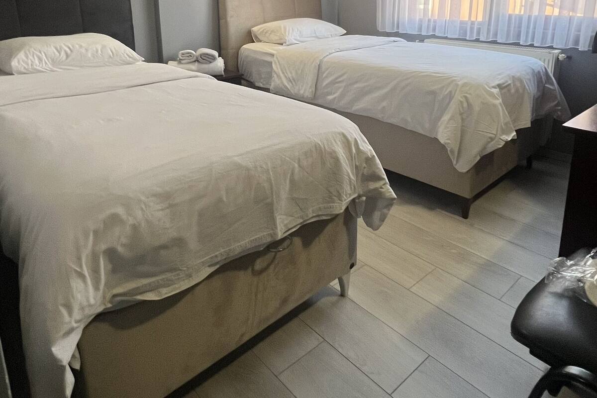 A hotel room with two beds, a desk, and a chair.