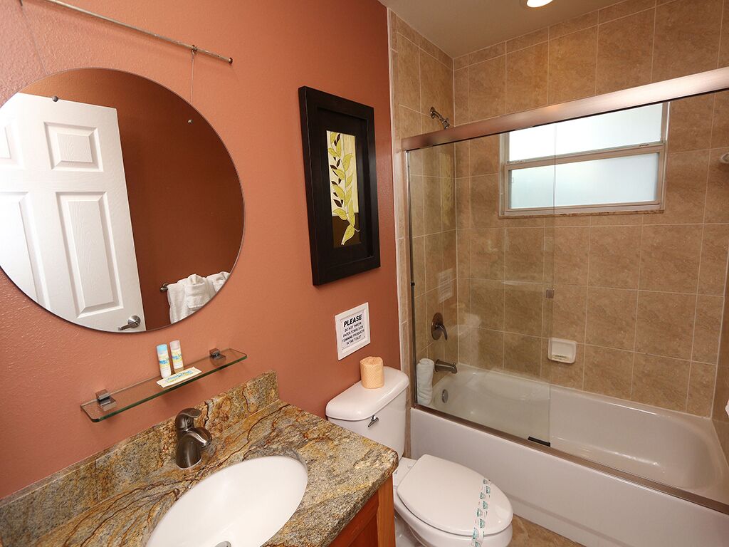 Une salle de bain avec un lavabo en marbre, des toilettes, une baignoire et une douche à l’italienne.