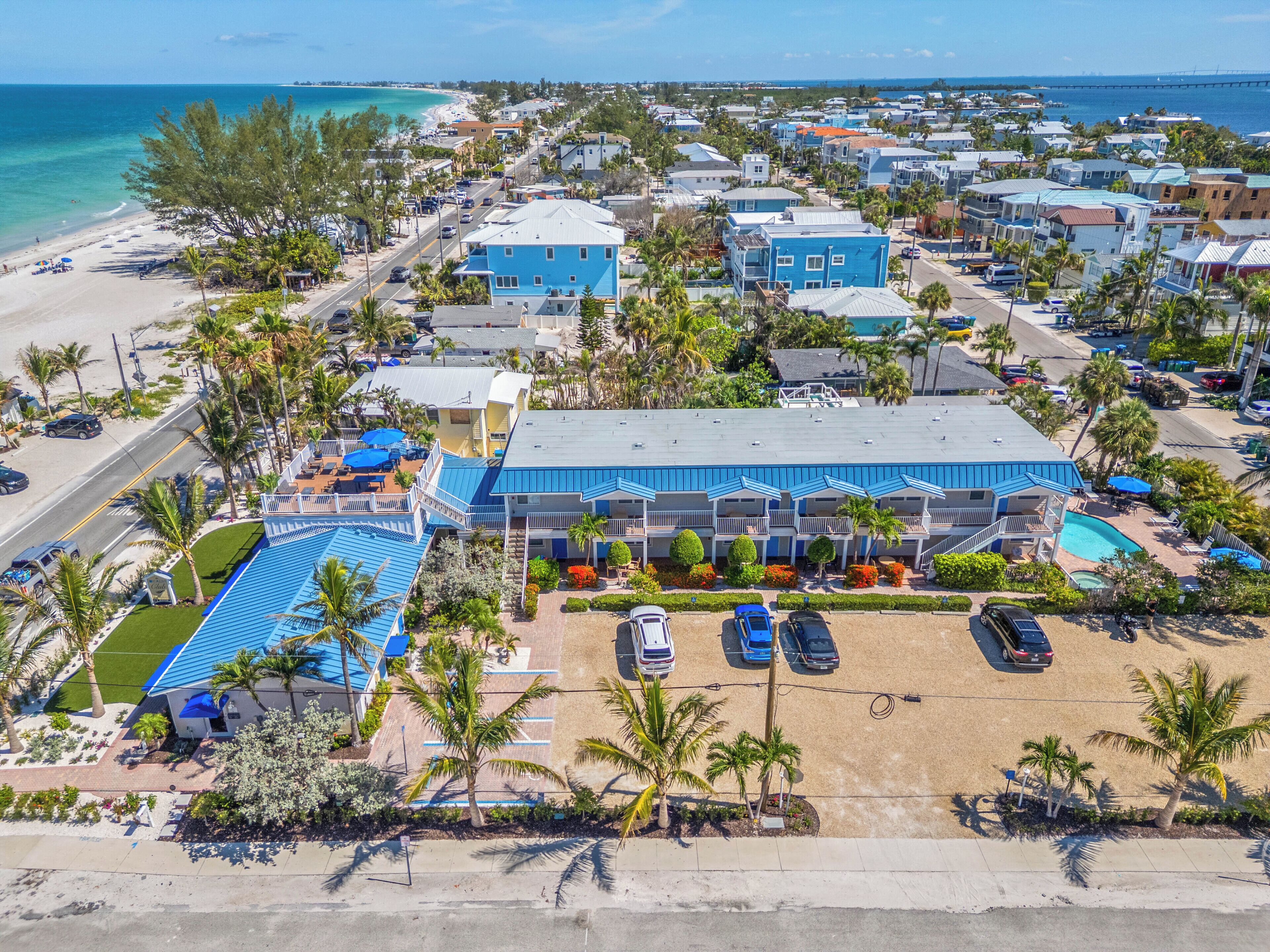 A beachfront hotel with multiple balconies, a swimming pool, and a parking area.