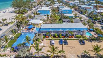A beachfront hotel with multiple balconies, a swimming pool, and a parking area.