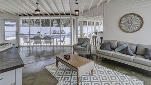 A spacious living area with a ceiling fan, a dining table with chairs, a sofa with cushions, and a decorative wall piece. - Sandy Feet Retreat: Family Friendly Charming Home with Private Pool (Hilton Head Island)