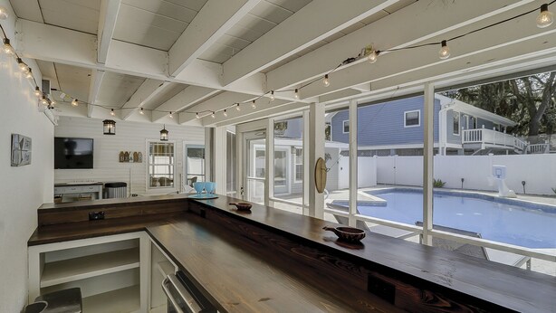 A kitchen with a large window overlooking a swimming pool, wooden countertops, and a built-in oven. - Sandy Feet Retreat: Family Friendly Charming Home with Private Pool (Hilton Head Island)