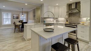 A modern kitchen with white cabinetry, a central island, stainless steel appliances, and recessed ceiling lights. - Sandy Feet Retreat: Family Friendly Charming Home with Private Pool (Hilton Head Island)