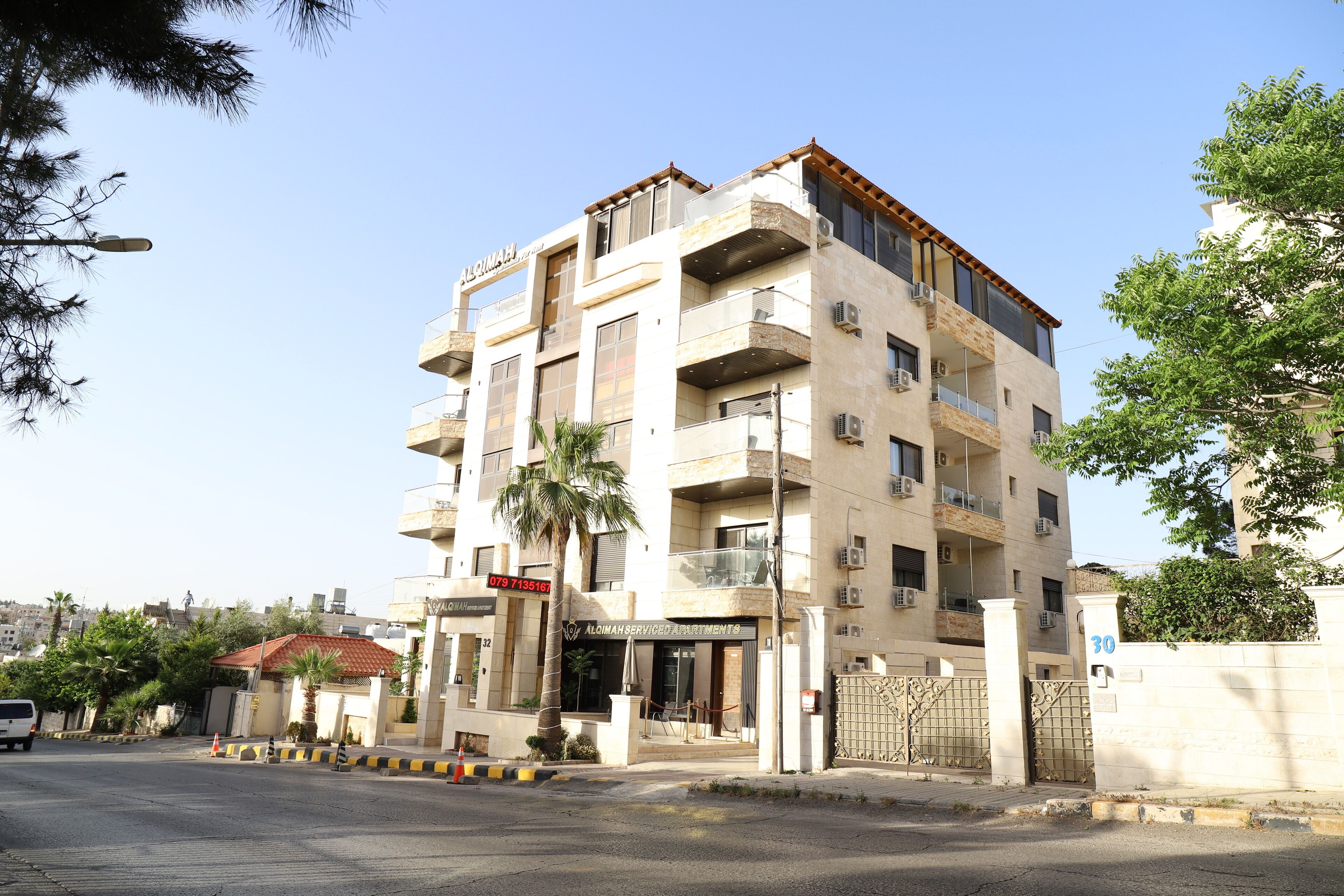 Un edificio de varios pisos con balcones, unidades de aire acondicionado y una entrada protegida por un portón.