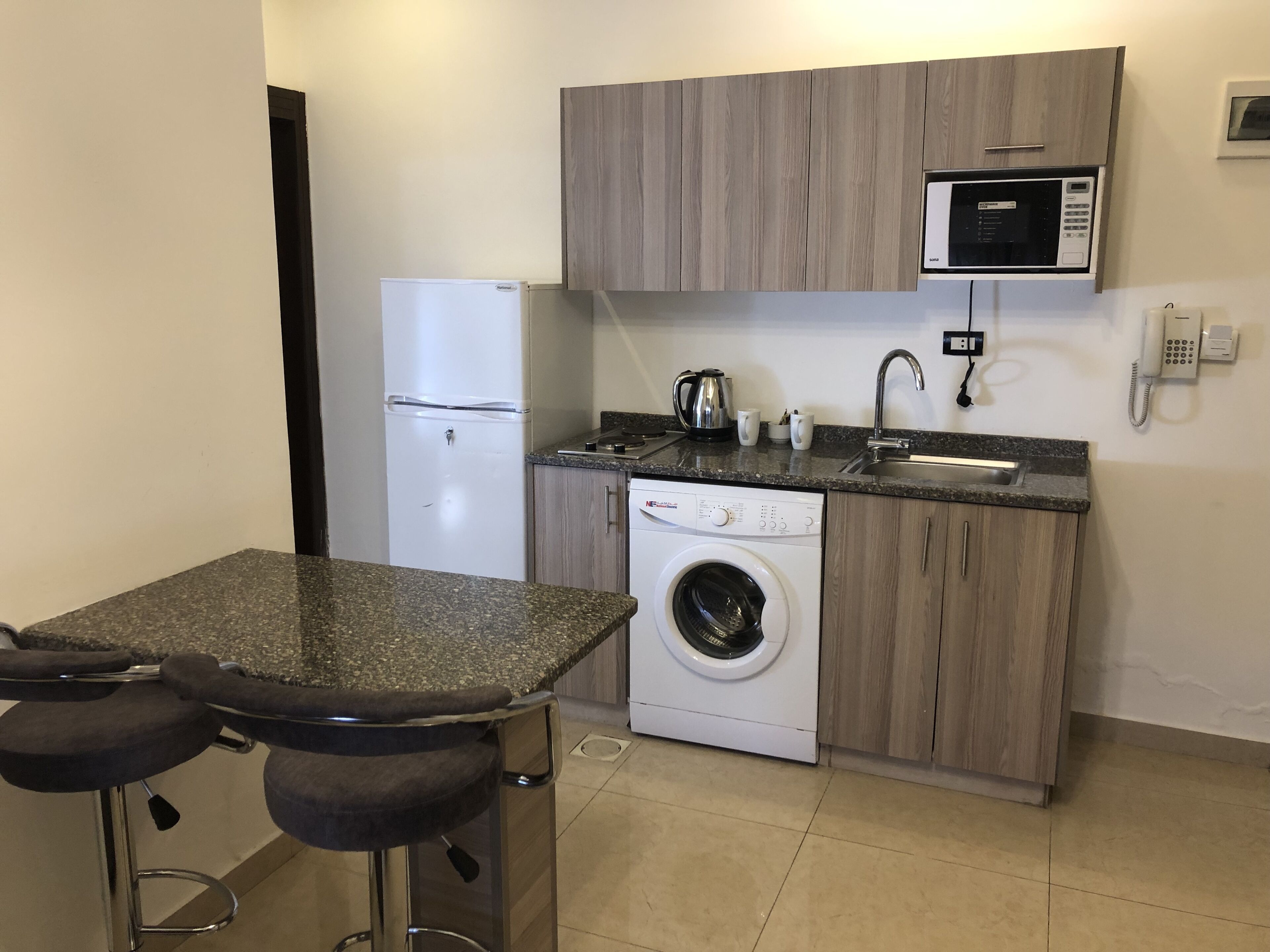 A compact kitchen with a built-in washing machine, a microwave, and a sink.