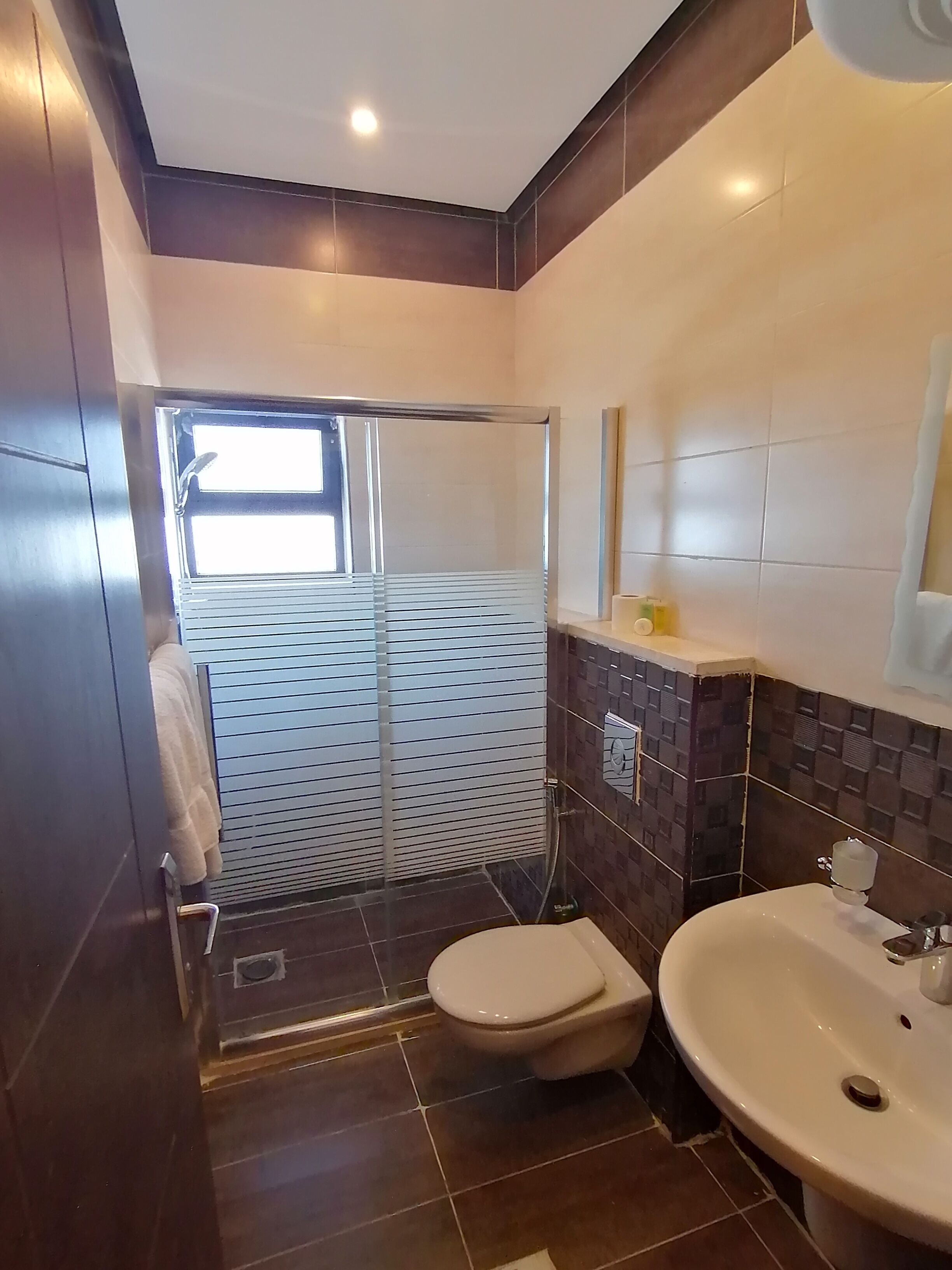 Un baño moderno con inodoro, lavamanos y zona de ducha.
