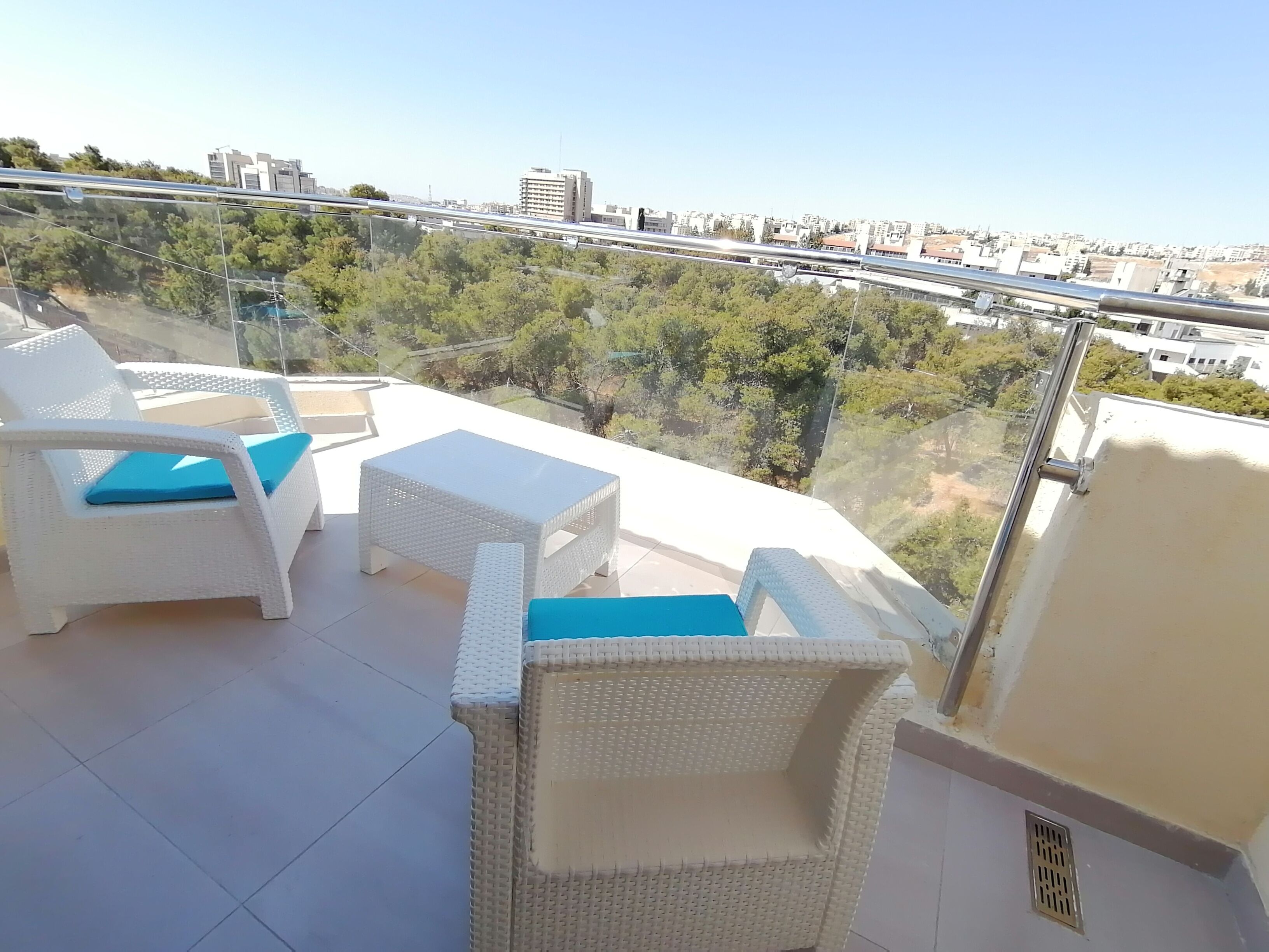 Een balkon met witte rieten meubels en een helder uitzicht op de skyline.