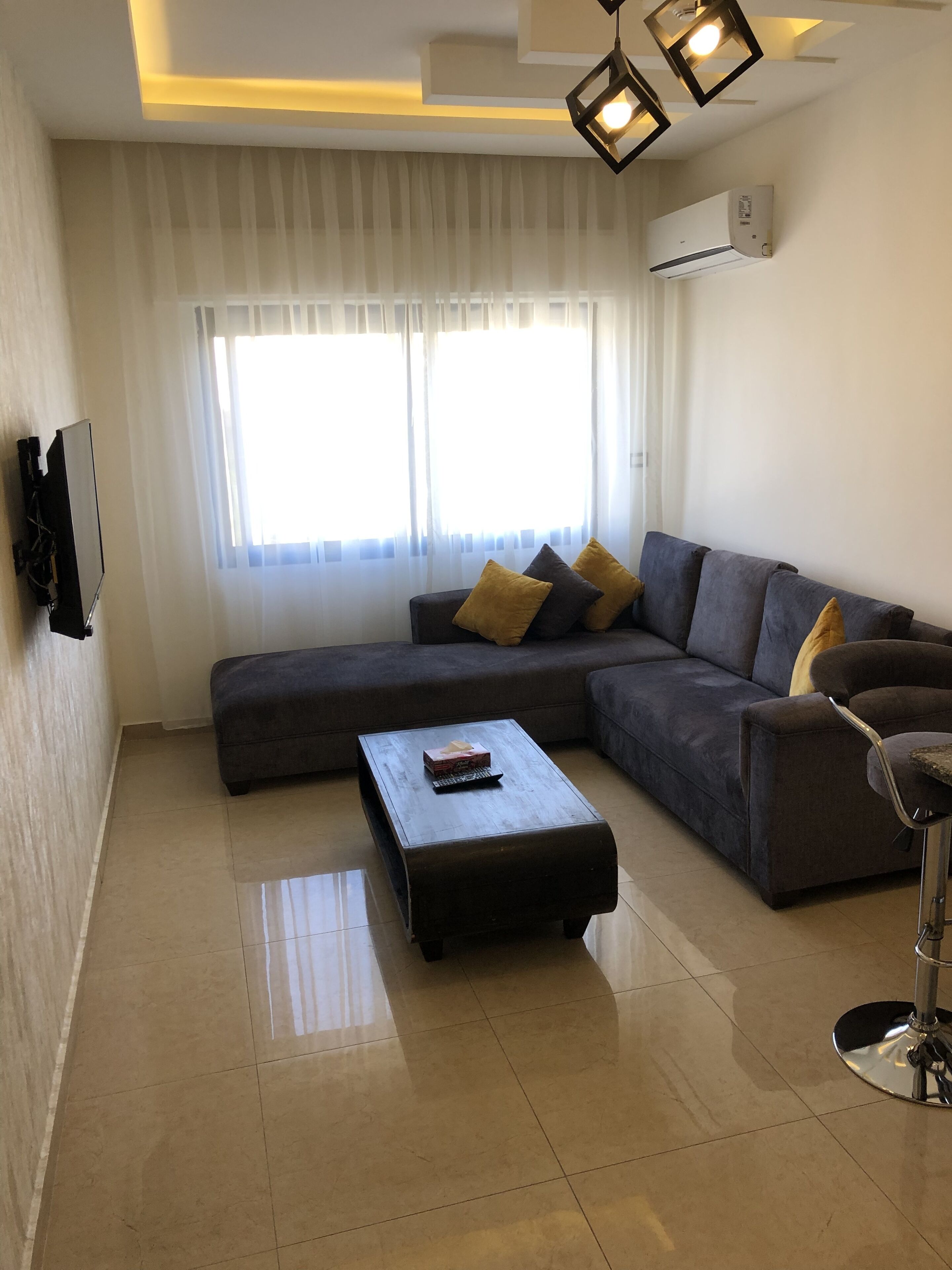 A modern living room with a sectional sofa, a coffee table, and a TV mounted on the wall.