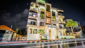 Un edifici de diverses plantes amb balcons i un rètol que diu "AJ.QIMAH".
