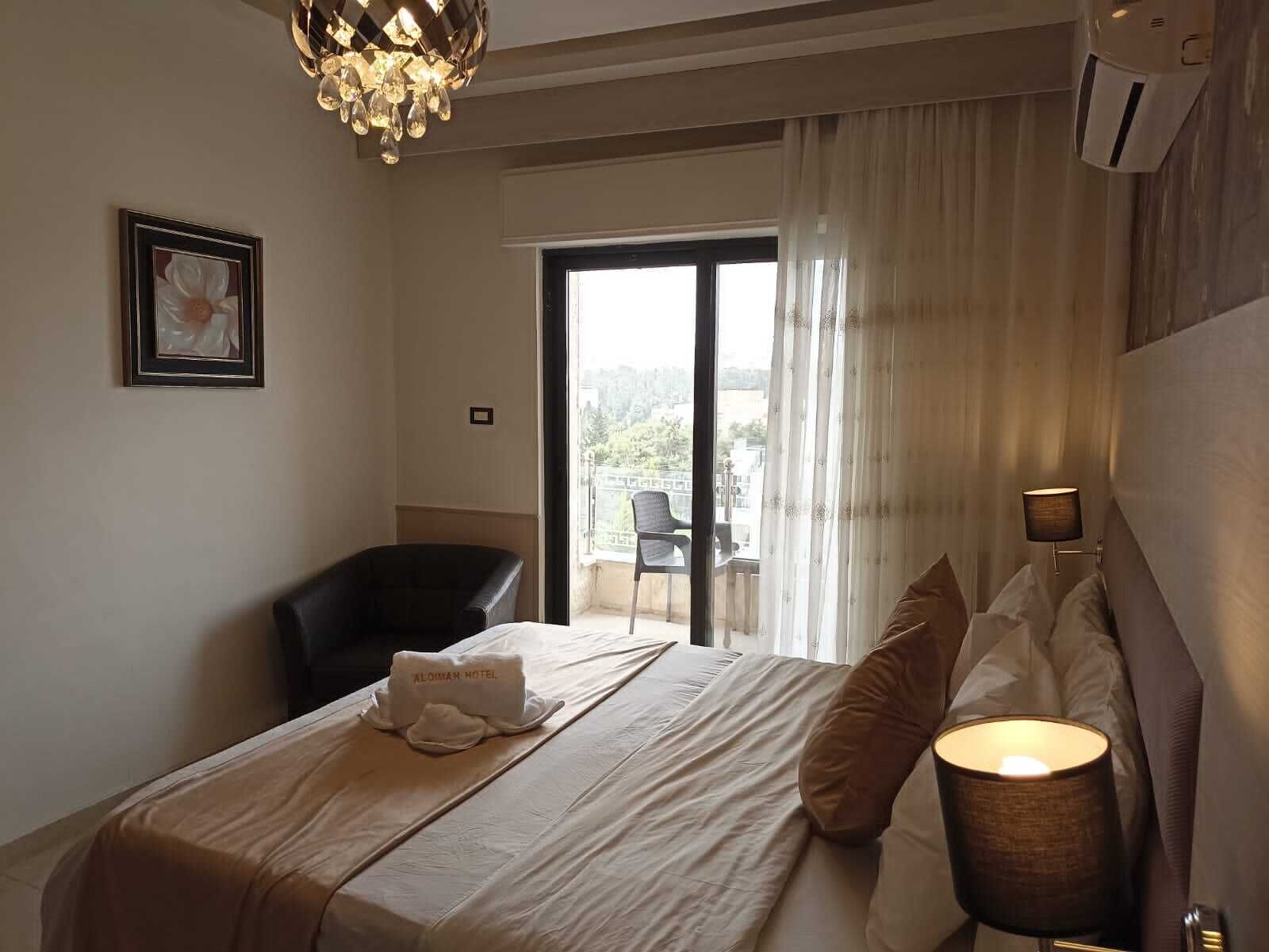 Une chambre d’hôtel avec un lit, une chaise, une lampe et une vue sur l’extérieur.
