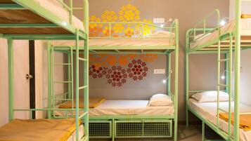 Quarto de dormitório com beliches, um lustre e um enfeite na parede.