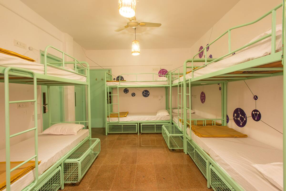 Ein Schlafsaalzimmer mit Etagenbetten, Deckenventilator und Wanduhr.