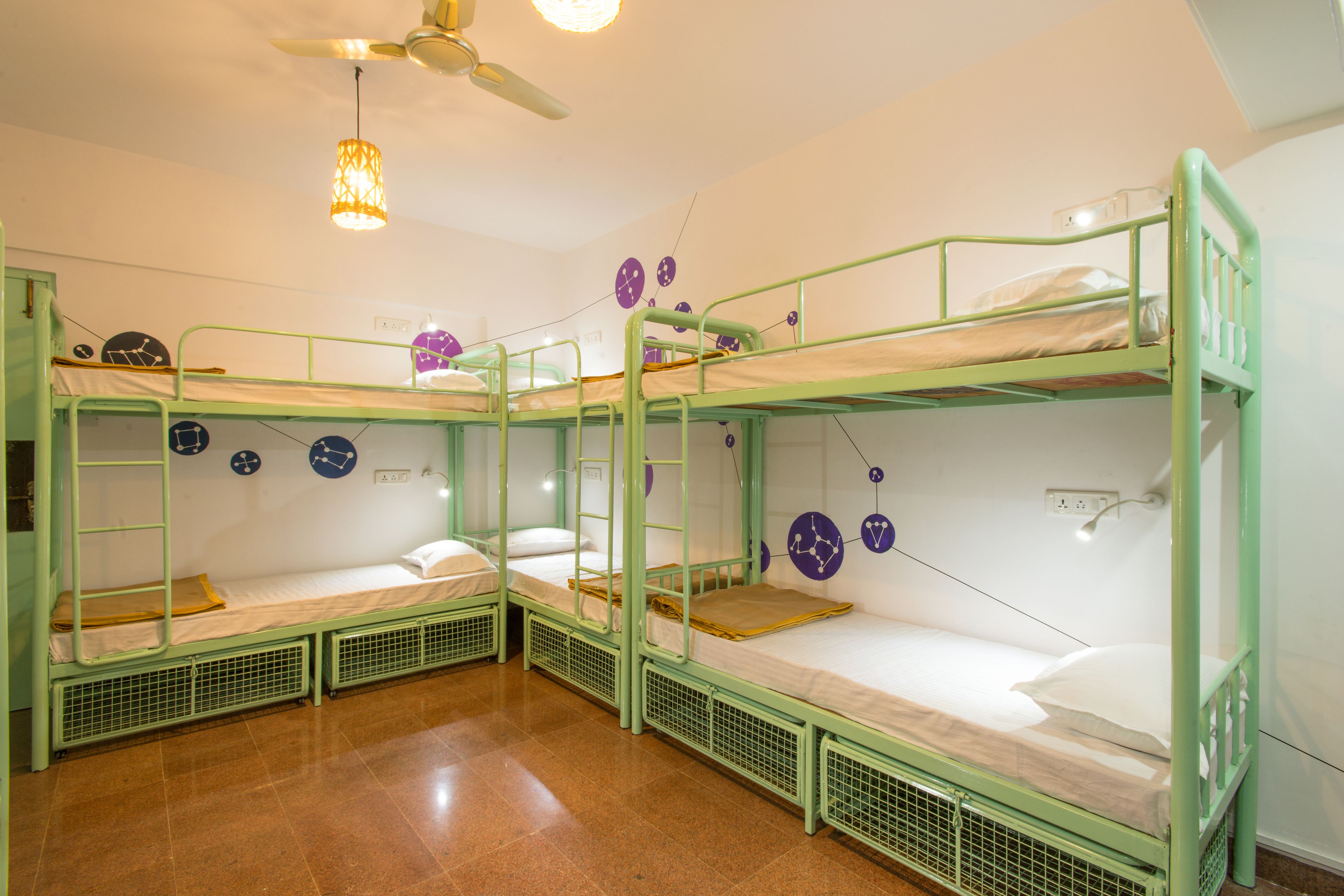 A dormitory room with bunk beds, a ceiling fan, and wall clocks.