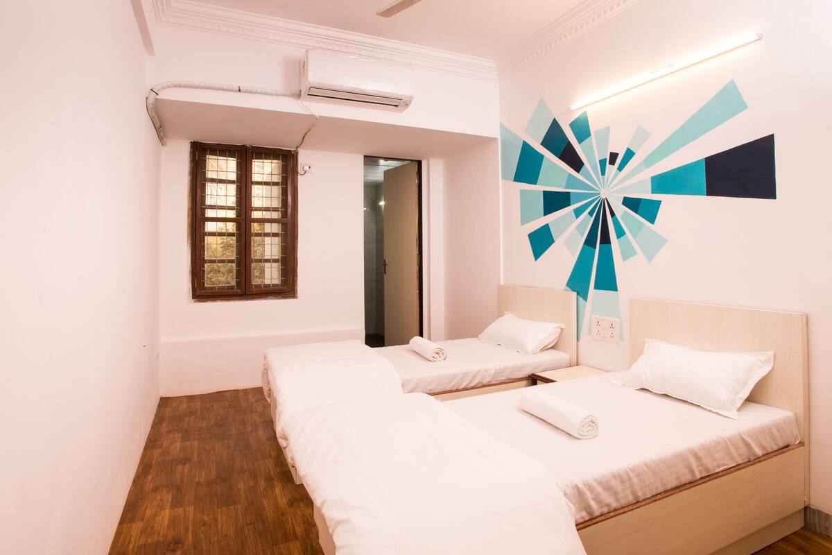 Ein Hotelzimmer mit zwei Betten, einem Fenster mit Blick, einer Klimaanlage und einer modernen Wanddekoration.