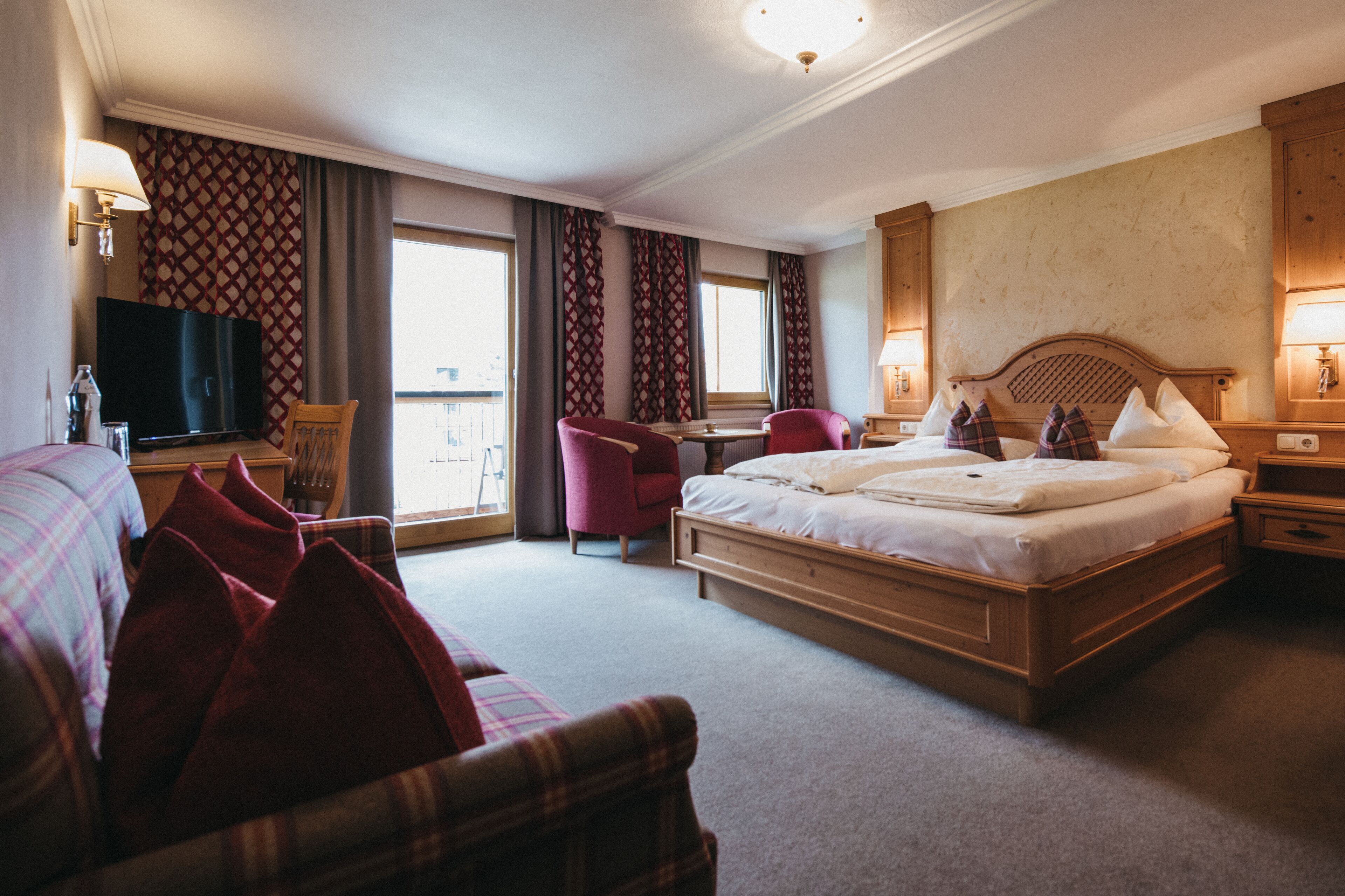 A hotel room with a large bed, a desk, a TV, and a chair.