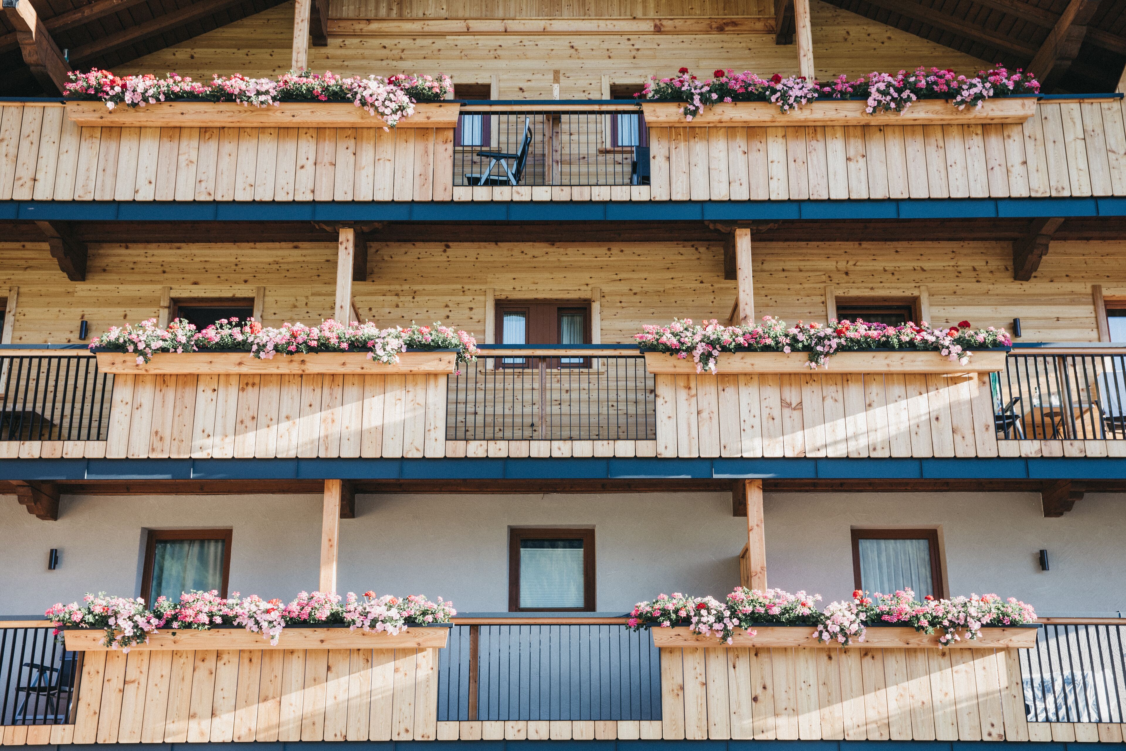 A multi-story wooden building with balconies adorned with flower boxes.