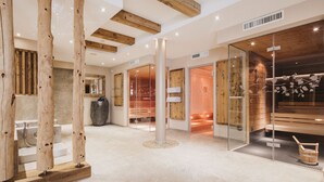 Interior moderno de spa con vigas de madera, sauna y sala de vapor con paredes de vidrio.