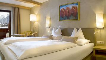 A hotel room with two beds, a painting of tulips, a desk, and a chair.
