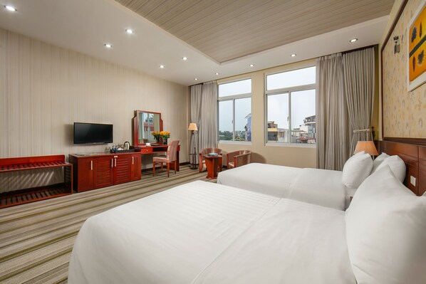 A hotel room with two beds, a desk, a TV, and a large window with curtains. - A25 Premium Hotel - 705 Lac Long Quan (Hanoi)