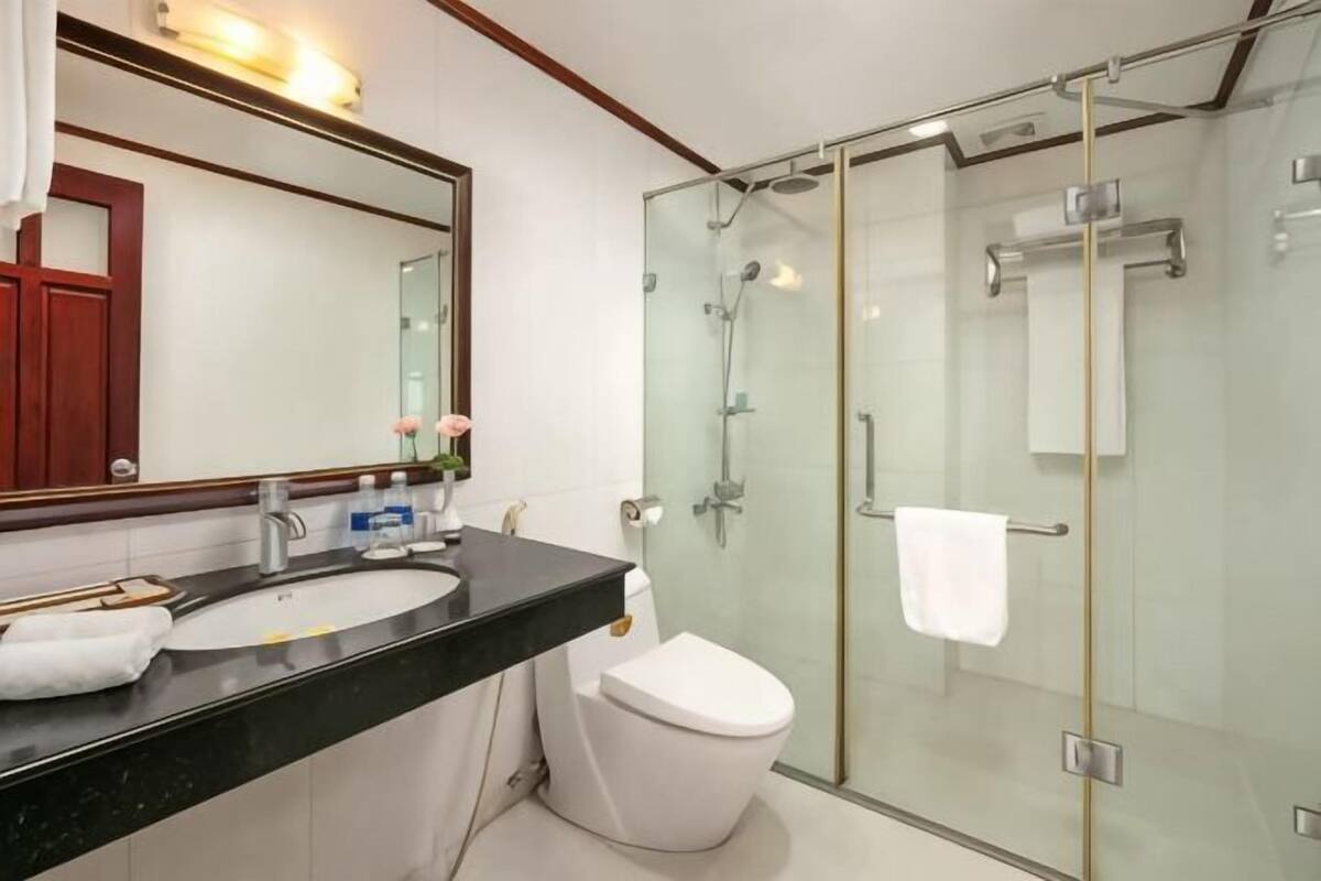 A modern bathroom with a glass shower enclosure, a white toilet, and a black countertop with a sink.