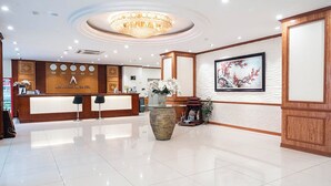 Un espace d’accueil d’hôtel au design moderne, agrémenté d’un lustre, d’un comptoir de réception et d’une œuvre d’art encadrée au mur.