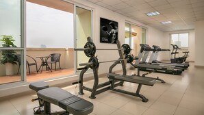 Une salle de sport équipée de matériel d’exercice, d’un banc et d’un mur orné d’une affiche.