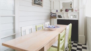 Un petit coin repas avec une table et des chaises en bois, un bol décoratif et un sol à carreaux.