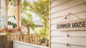 Une pancarte en bois portant l’inscription « SUMMER HOUSE » est accrochée à la façade d’une maison blanche.