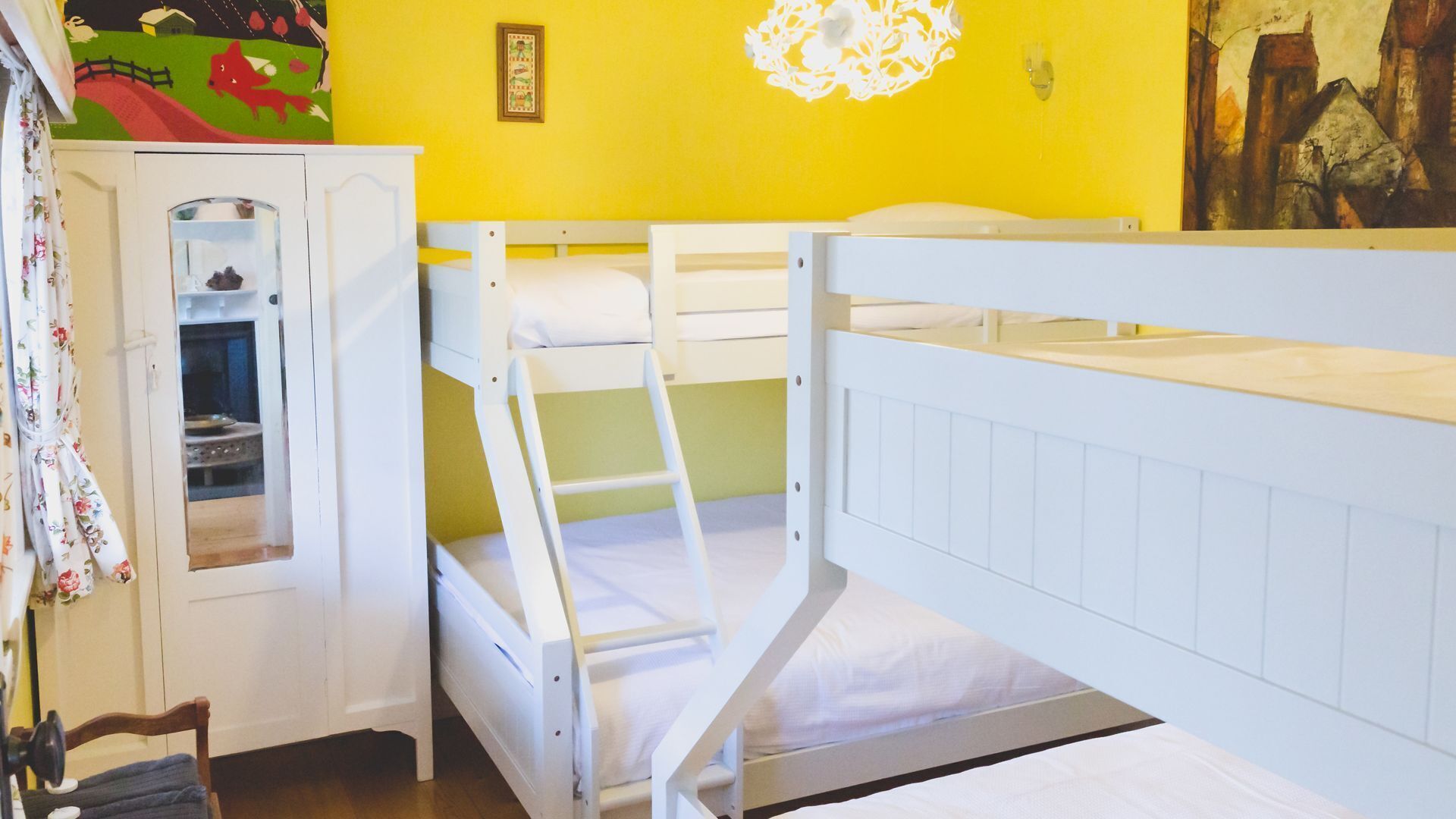 A child's bunk bed room with a cabinet and a painting on the wall.