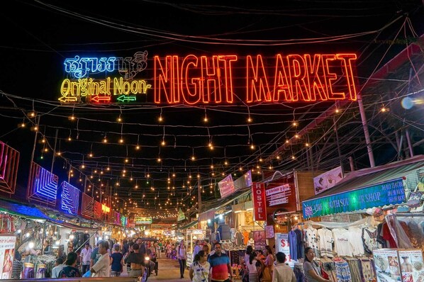 A bustling night market with neon signs and string lights. - Siem Reap Homesteading (Siem Reap)
