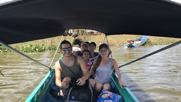 A boat with passengers, including a child and an adult, on a river. - Siem Reap Homesteading (Siem Reap)