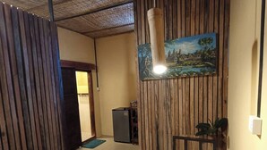 A reception area with a wooden desk, a painting of a landscape, a small plant, and a door leading to another room. - Siem Reap Homesteading (Siem Reap)