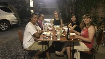 A group of people dining at an outdoor table with a variety of dishes and drinks.