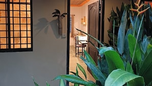A hallway with a ceiling fan, a window with a grid pattern, and a door leading to a room with a desk and a laptop. - Siem Reap Homesteading (Siem Reap)