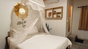 A bed with a white canopy, a wall-mounted air conditioner, a small shelf with decorative items, and a window with curtains. - Siem Reap Homesteading (Siem Reap)