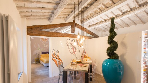 A dining area with a wooden ceiling, a large blue vase, and a wall with butterfly art. - Fonte Gaia Experience B&B (Siena)