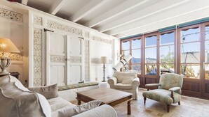 A spacious living room with a high ceiling, a large window with a view of the outdoors, and a fireplace. - Mallorca One by Balearic Villas (Pollensa)